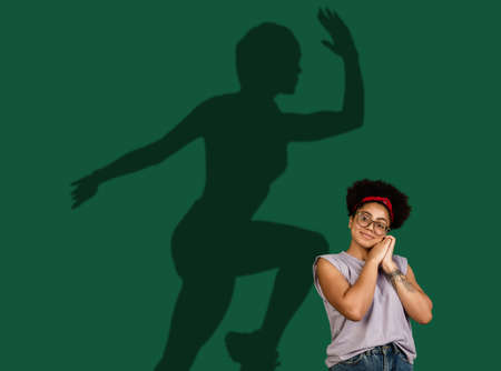 Young woman dreaming about future in big sport. Becoming a legend. Shadow of dreams on the wall...
