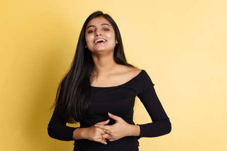 Emotional young adorable cute girl, student in black blouse posing isolated on yellow color studio...