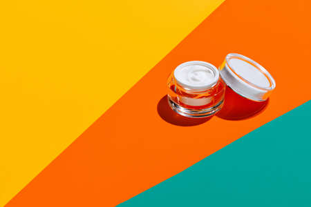 Jars of facial cosmetic cream with copy space for your brand isolated on bright colored background. Mockupの写真素材