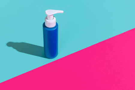 One blue pump bottle for cosmetics product, cream, lotion without logos standing isolated over magenta blue background.の写真素材