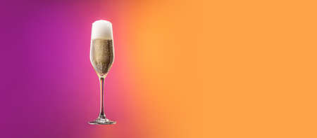 Glass with cold champagne with bubbles isolated over gradient purple and orange color background in neon. Concept of alcohol, holidays, New Yearの写真素材