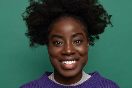 Close up dark skinned smiling girl on dark green studio background. Afro hairdo. Concept of emotions, facial expressionsの写真素材