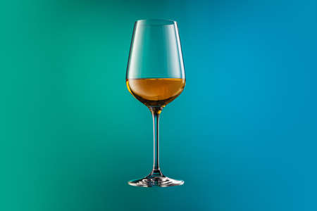 Image of white wine glass isolated over gradient blue and green color background in neon. Concept of alcohol, holidays, New Yearの写真素材