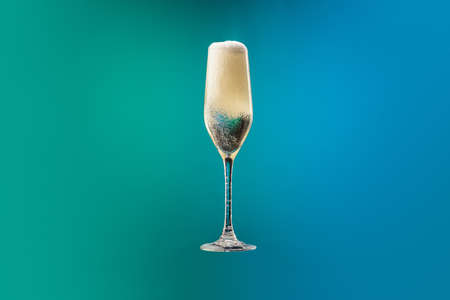 Champagne flute with bubbles and foam isolated over gradient blue and green color background in neon. Concept of alcohol, holidays, New Yearの写真素材