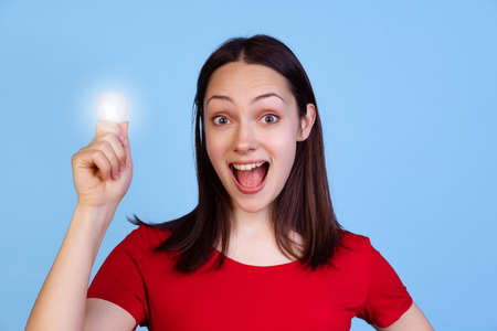 Half-length portrait of cute pretty young woman in red t-shirt isolated on blue studio background. Concept of emotionsの写真素材