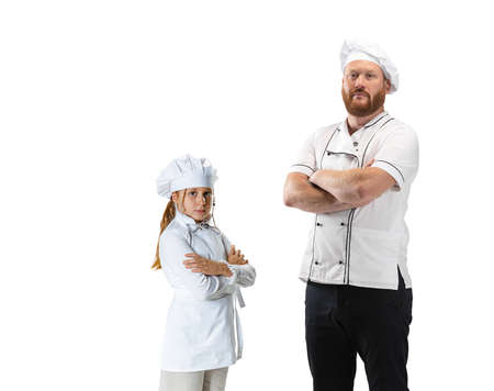 Young bearded man, cook, male chef in white uniform and his little assistant, child having fun isolated on white background.の写真素材