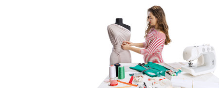 Smiling cute young girl, seamstress, dressmaker working with fabric, scissors and sewing machine...