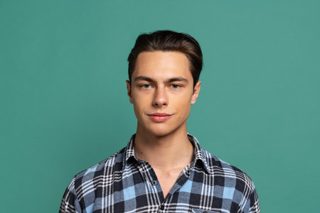 Handsome happy man, student wearing warm plaid shirt looking at camera isolated on green studio background.の写真素材