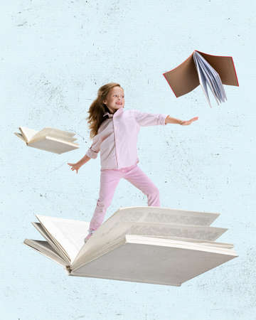 Contemporary art collage of little cheerful girl, child surfing on open book isolated over light blue backgroundの写真素材