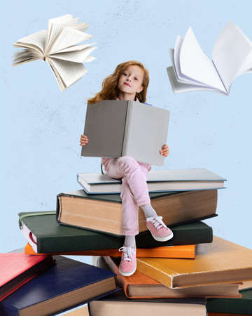 Contemporary art collage of little girl sitting on books and reading isolated over blue backgroundの写真素材