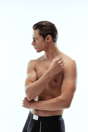 Half-length portrait of young handsome shirtless sportive man wearing black boxer-briefs standing isolated on white background.の写真素材