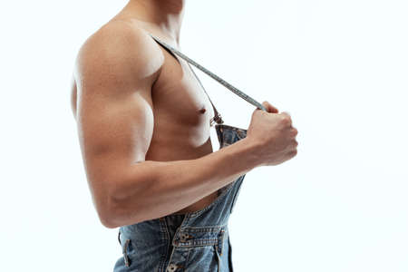 Cropped image of young sportive shirtless man in jeans posing isolated on white studio background.の写真素材