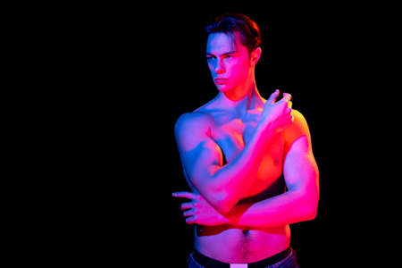 Handsome young mans portrait isolated on dark studio background in pink neon, Concept of human...