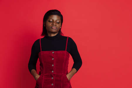 Sad young dark skinned girl isolated on dark red studio background. Concept of emotions, facial expressionsの写真素材