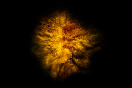 Explosion of yellow, golden color, fluid and neoned powder on dark studio background with copy spaceの写真素材
