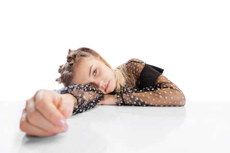 Close-up beautiful little cute girl, pupil in black dress sitting at table isolated on white studio...