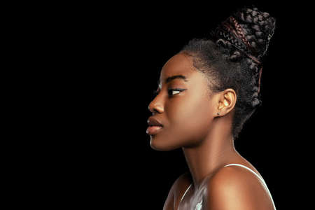 Adorable young african woman with well-kept skin isolated over dark studio background. Natural...