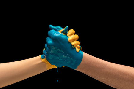 Two painted human hands handshaking isolated on dark studio background. Concept of human relation, symbolism, culture and historyの写真素材