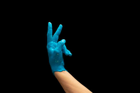 Male hand painted blue gesturing isolated on dark studio background. Concept of human relation,...
