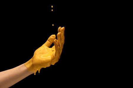 Yellow painted human hand gesturing isolated on dark studio background. Concept of human relation, symbolism, culture and historyの写真素材