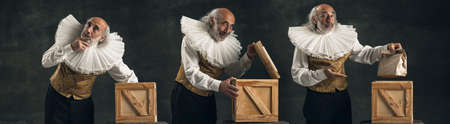 Mystery, magic. Elderly gray-haired man, actor or magician isolated on dark vintage background....