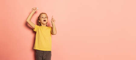 Emotive cute little girl, pupil holding bulb posing isolated on pink background. Concept of...