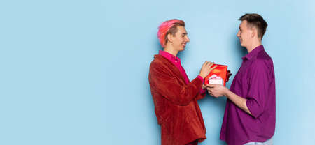 Portrait of young men, couple posing isolated on blue background. Valentines day celebration....