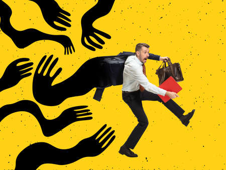 Scared young man, business man running away from giant drawn black creeping arms. Contemporary art collage. Concept of manipulation or addictionの写真素材