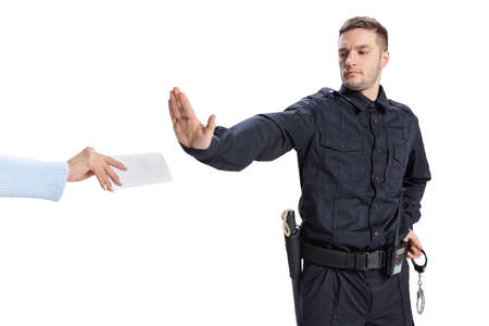Portrait of young man, policeman wearing black uniform refuses a bribe isolated on white background....