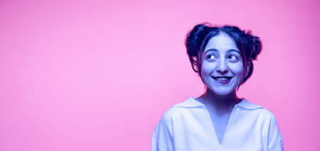 Cute young arabian girl in white blouse isolated on pink background in neon. Concept of emotions, problems, inner worldの写真素材