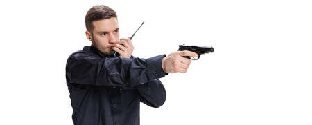 Half-length portrait of young man, policeman officer wearing black uniform standing with gun...