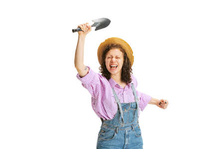 Excited young girl, gardener in work uniform and hat posing isolated on white background. Concept of...