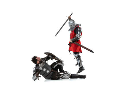 Portrait of two men fighting, medieval warror attacking with sword another knight isolated over white studio backgroundの写真素材