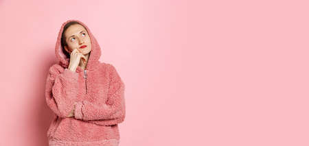 Dreams. Half-length portrait of young woman, student with short hair in pearch color hoodie isolated on pink background. Concept of emotions, studying, adの写真素材
