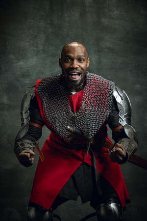 Half-length portrait of dark skinned man, medieval warrior or knight wearing armour shouting as...