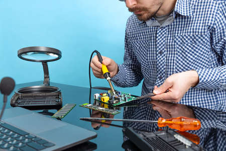 Cropped image of male hands working with motherboard isolated over blue backgroundの写真素材