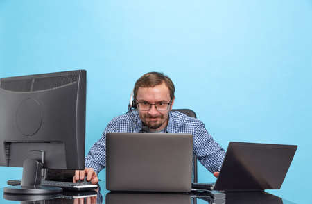 Portrait of concentrated man, programmer, computer system analyst working with operating sytem isolated over blue backgroundの写真素材