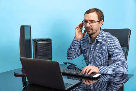 Portrait of concentrated man, call center operator working answering online call isolated over blue backgroundの写真素材