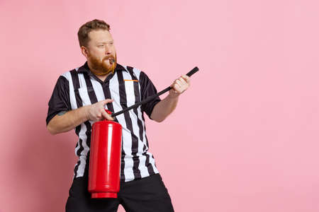 Comic portrait of sport referee wearing field judge uniform isolated on pink studio background. Concept of sport, rules, competitions, rights, ad, sales.の写真素材