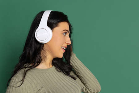 Profile view. Happy young beautiful girl with long glossy dark hair listening to music isolated on...