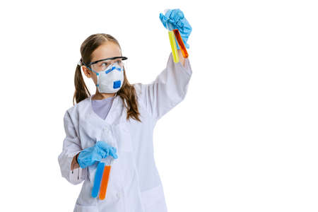 Researcher. One school girl, kid in white big gown as chemist, scientist doing experiment with multicolored chemical fluid in laboratory isolated on white backgroundの写真素材