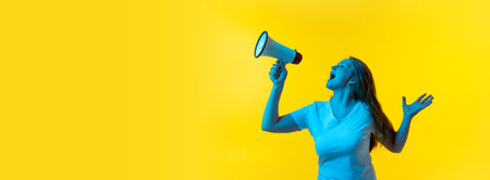 Flyer with beautiful young girl with freckles on her face shouting at megaphone isolated on yellow background in neon. Concept of wow emotions, ads, salesの写真素材