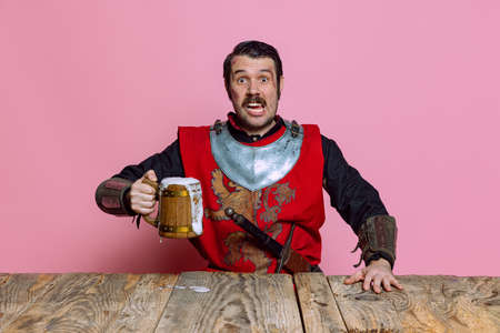Portrait of medieval warrior or knight with dirty wounded face holding huge mug of beer isolated...
