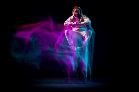 One energy young flexible sportive man dancing hip-hop or breakdance in white outfit on dark background in mixed blue neon light. Sport, art, action, movesの写真素材
