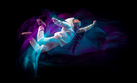 One energy young flexible sportive man dancing hip-hop or breakdance in white outfit on dark background in mixed blue neon light. Sport, art, action, movesの写真素材
