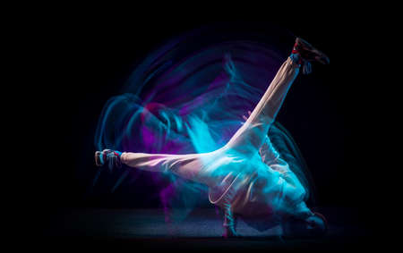 One energy young flexible sportive man dancing hip-hop or breakdance in white outfit on dark background in mixed blue neon light. Sport, art, action, movesの写真素材