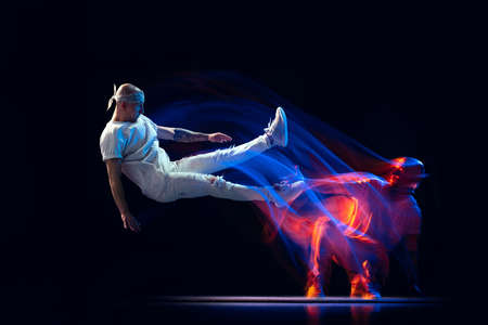 Split personality. Sportive man in sports white uniform and do-rag dancing hip-hop isolated on dark...