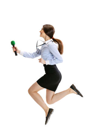 At interview. Female journalist holding reporter microphone jumping isolated on white studio background. Concept of social media, press, news, informationの写真素材