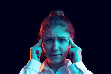 Half-length portrait of young pretty girl in white shirt isolated on dark background in blue neon light, filter. Concept of emotions, fashion, youthの写真素材