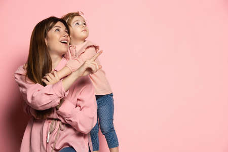 Dreams. Portrait of young woman and little girl, mother and daughter isolated on pink studio background. Mothers Day celebration. Concept of family, childhood, motherhoodの写真素材